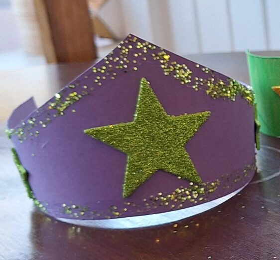 Purple paper crown with a green star on it.