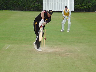 A cricket player hitting a ball.
