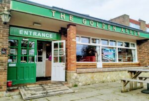 The outside of the Golden Arrow pub in Golden Valley. It isa painted green and the door is open.