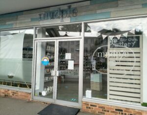 The outside of Mudpie Pottery that does Pottery painting in Sandgate. It has glass doors and huge glass windows.