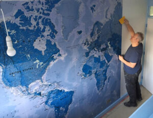 Lammas Master Decorator at work putting up a world map for The Wallpaper Emporium